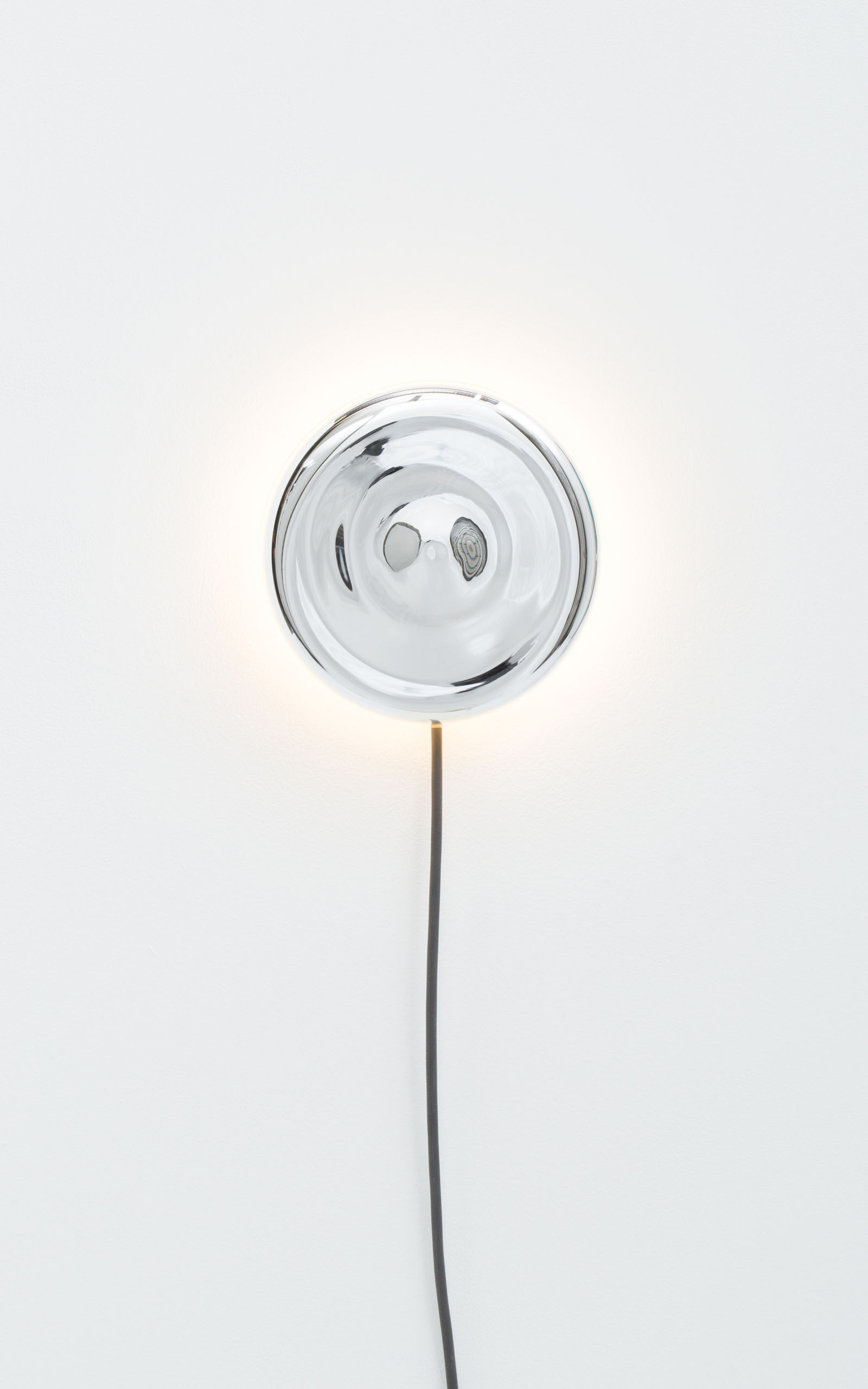 A wall mounted light that consists of a silver plated mirror disc with the light emitting from behind.